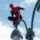 Peter Parker, in costume as Spider-Man, sits perched atop a New York City street lamp.